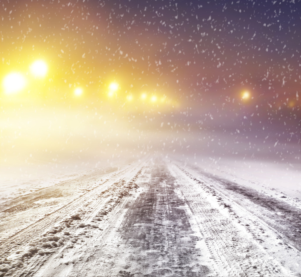 Snow covered winter road with shining streetlights at night